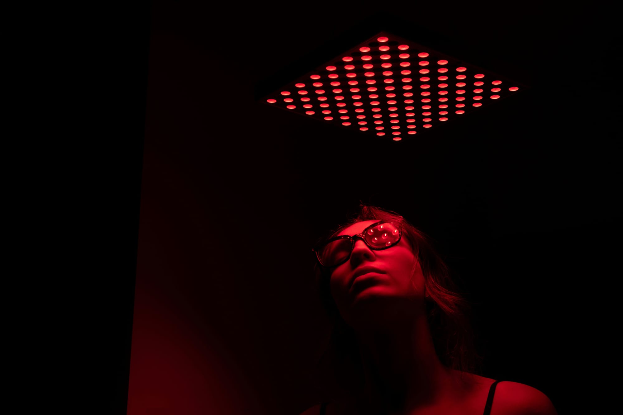 An image of a person appearing female in a dark room with only red light.