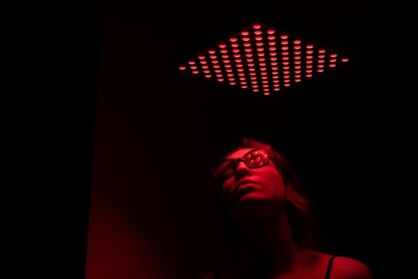 An image of a person appearing female in a dark room with only red light.