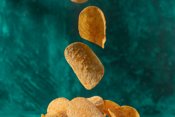 Image of chips falling into a bowl on a green background.